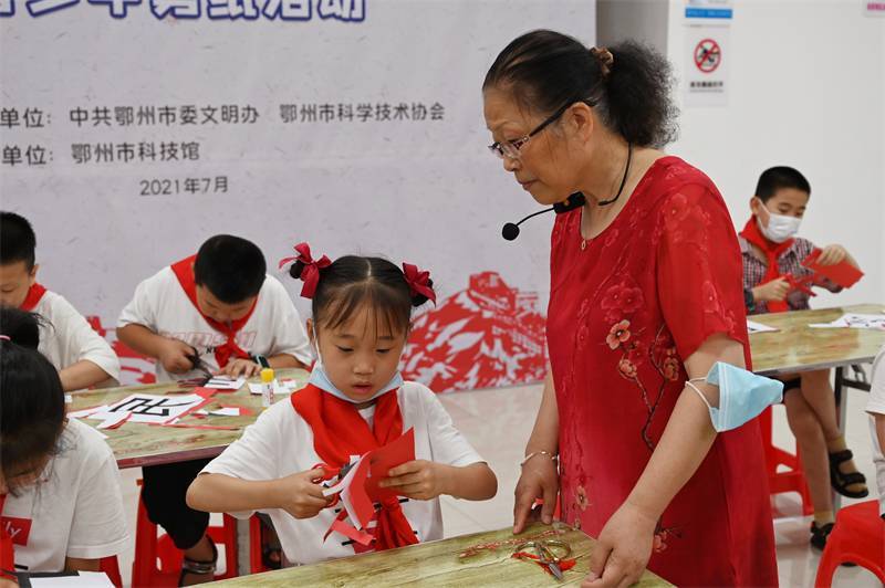 2021年7月10日，鄂州市科協(xié)組織落駕坪小學(xué)學(xué)生在鄂州市科技館開展社會主義核心價(jià)值觀系列活動，圖為開展的紅色剪影圓夢中華剪紙活動，老師指導(dǎo)同學(xué)剪紙.jpg
