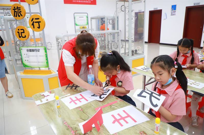 2021年7月10日，鄂州市科協(xié)組織落駕坪小學(xué)學(xué)生在鄂州市科技館開展社會主義核心價(jià)值觀系列活動，圖為開展的紅色剪影圓夢中華剪紙活動，志愿者指導(dǎo)同學(xué)們.jpg